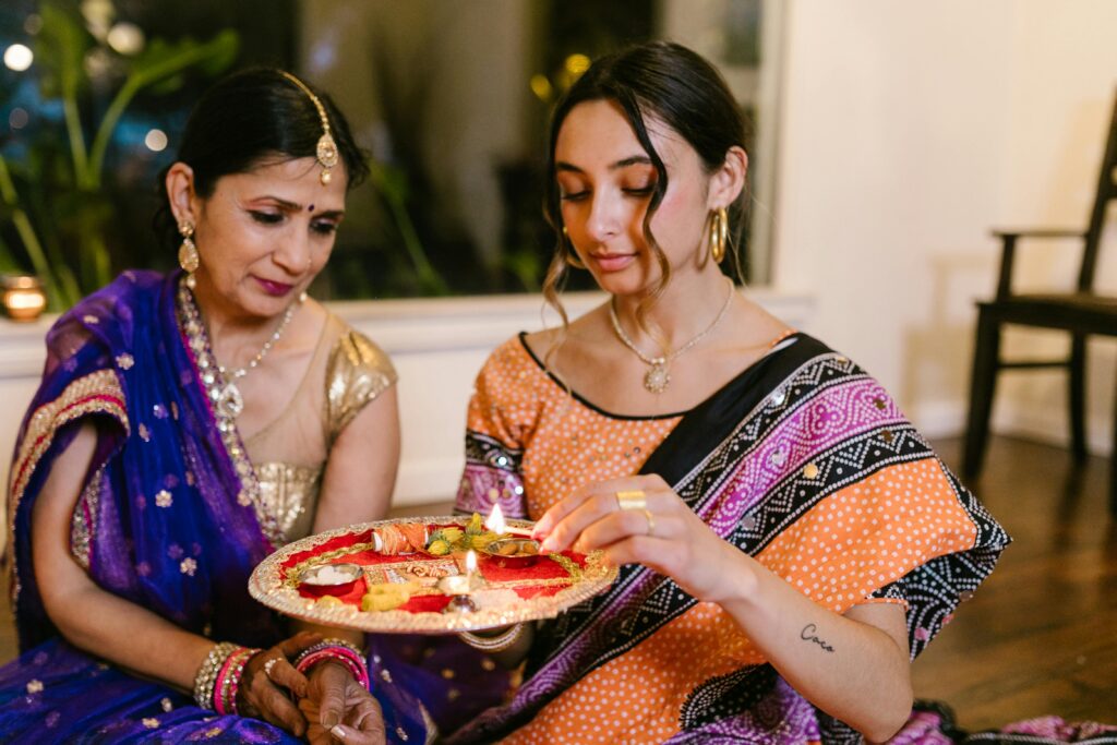 Mother and daughter performing a Diwali ritual with a lit puja plate, showcasing traditional Indian culture. Where to go this Diwali in Dubai